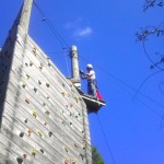 Inspector working on a Climbing Wall. Inspection practices and other Challenge Course Information can be found within our blog.
